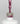 Nahaufnahme einer offenen Longlife UV-Lack Glam Glitter Lillet Berry Flasche. Die Farbe ist ein dunkles Rosa mit sehr viel Glitzer. Der UV-Nagellack tropft am Pinsel herunter.