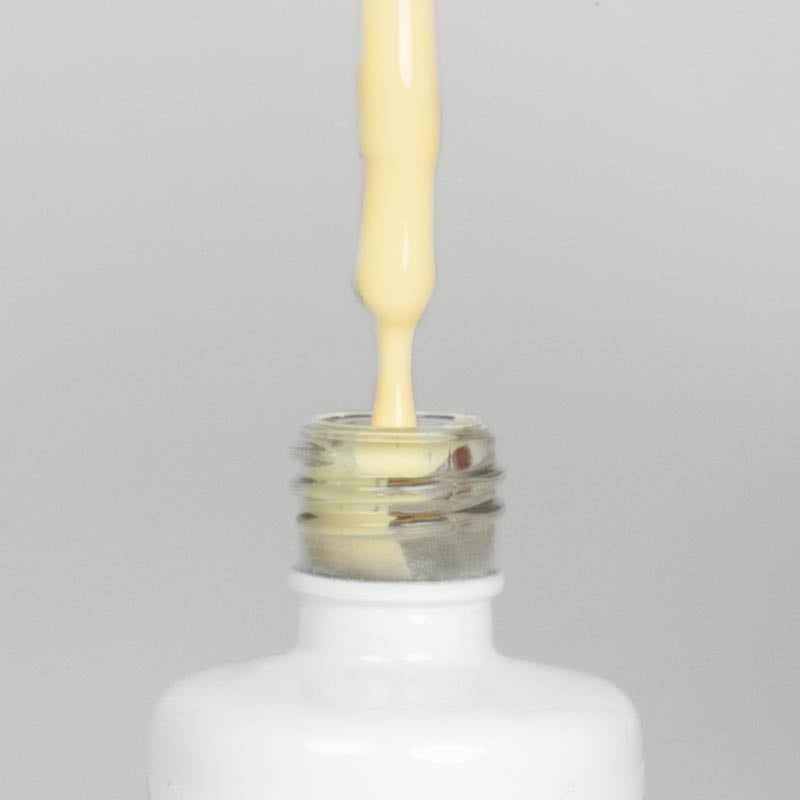 Nahaufnahme einer offenen Longlife UV-Lack Allure Flasche. Die Farbe ist ein helles Gelb. Der UV-Nagellack tropft am Pinsel herunter.
