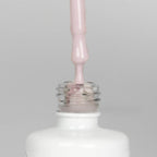 Nahaufnahme einer offenen Longlife UV-Lack Almost Mauve Flasche. Die Farbe ist ein helles kühles Rosa. Der UV-Nagellack tropft am Pinsel herunter.