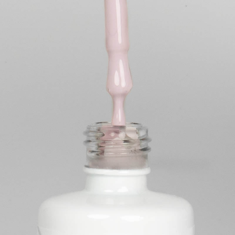 Nahaufnahme einer offenen Longlife UV-Lack Almost Mauve Flasche. Die Farbe ist ein helles kühles Rosa. Der UV-Nagellack tropft am Pinsel herunter.