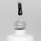Nahaufnahme einer offenen Longlife UV-Lack Base/Top Flasche. Die Farbe ist transparent. Der UV-Nagellack tropft am Pinsel herunter.