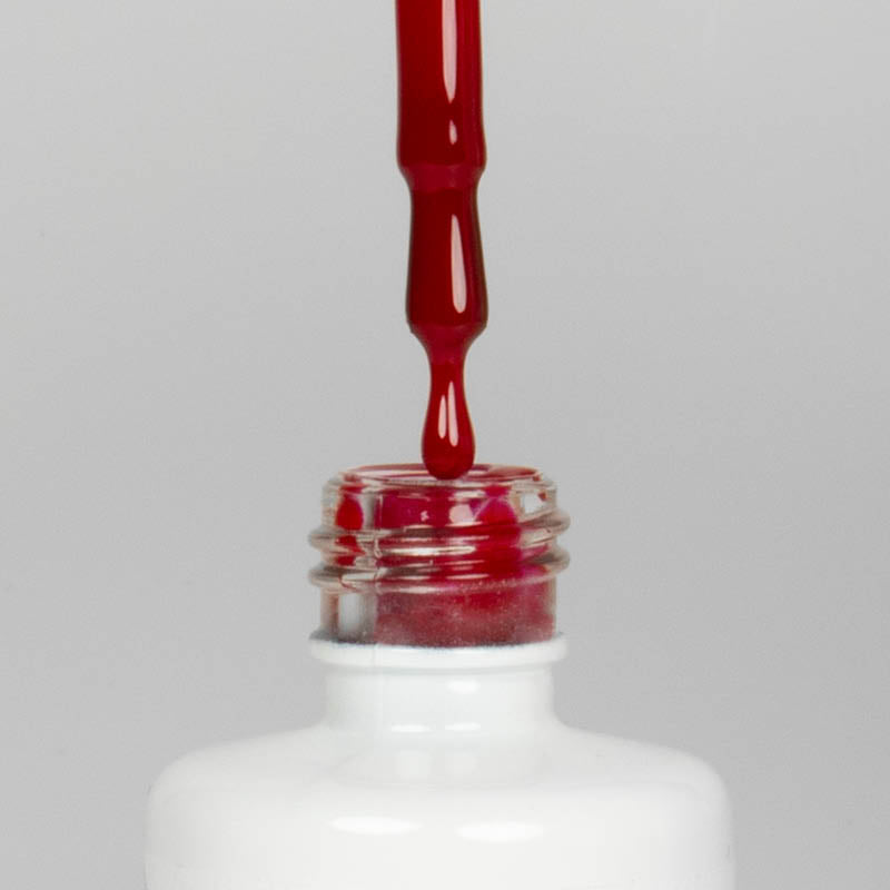 Nahaufnahme einer offenen Longlife UV-Lack Beets Flasche. Die Farbe ist ein dunkles Rot mit Pink-Stich. Der UV-Nagellack tropft am Pinsel herunter.