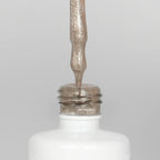 Nahaufnahme einer offenen Longlife UV-Lack Bella Bianca Flasche. Die Farbe ist ein Nude mit Metallic Effekt. Der UV-Nagellack tropft am Pinsel herunter.