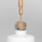 Nahaufnahme einer offenen Longlife UV-Lack Bella Elvira Flasche. Die Farbe ist ein Gold mit Metallic Effekt. Der UV-Nagellack tropft am Pinsel herunter.