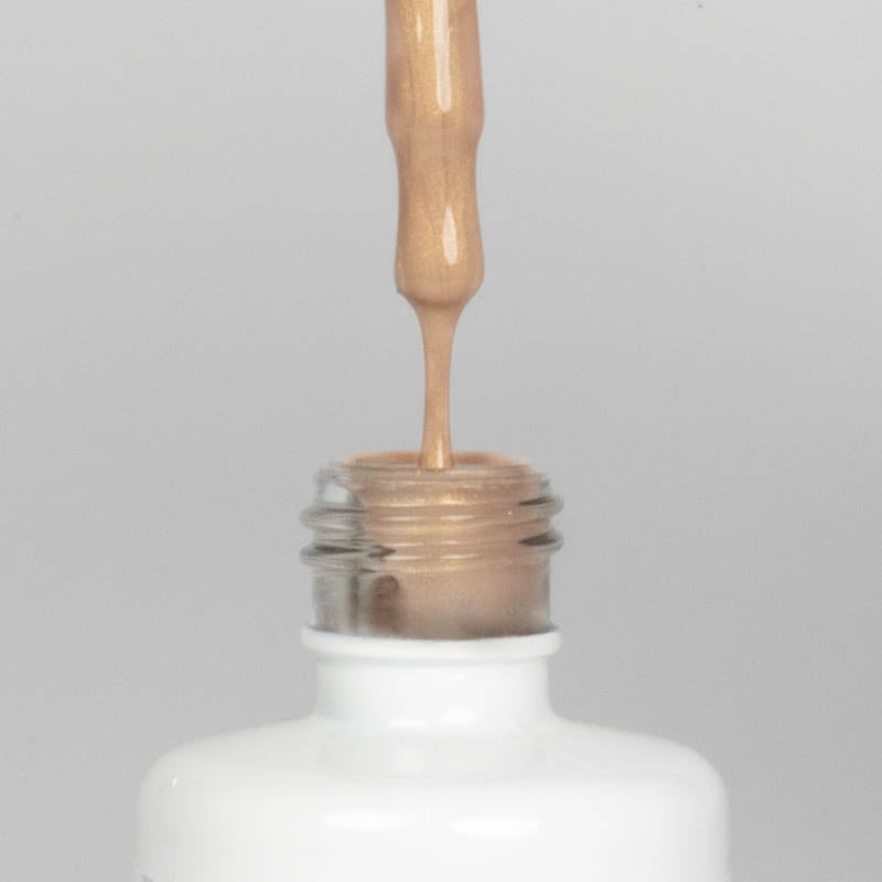 Nahaufnahme einer offenen Longlife UV-Lack Bella Elvira Flasche. Die Farbe ist ein Gold mit Metallic Effekt. Der UV-Nagellack tropft am Pinsel herunter.