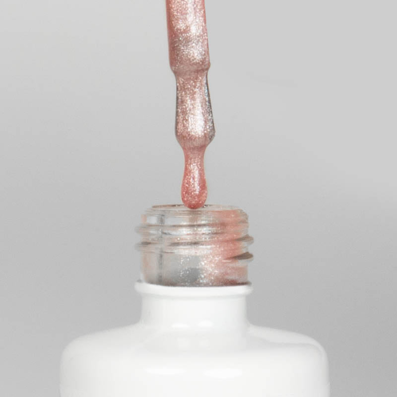Nahaufnahme einer offenen Longlife UV-Lack Bella Kim Flasche. Die Farbe ist ein rosé-nude mit Glitzer Effekt. Der UV-Nagellack tropft am Pinsel herunter.