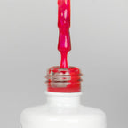 Nahaufnahme einer offenen Longlife UV-Lack Bella Michele Flasche. Die Farbe ist ein Pink mit Metallic Effekt. Der UV-Nagellack tropft am Pinsel herunter.