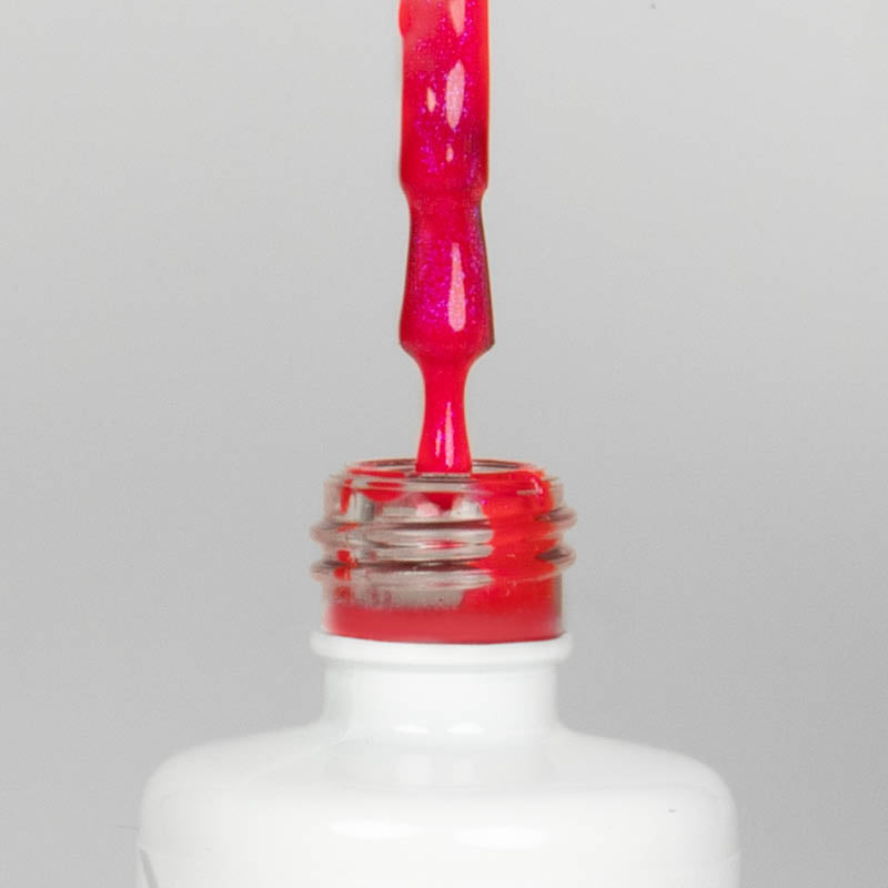 Nahaufnahme einer offenen Longlife UV-Lack Bella Michele Flasche. Die Farbe ist ein Pink mit Metallic Effekt. Der UV-Nagellack tropft am Pinsel herunter.