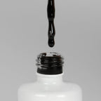 Nahaufnahme einer offenen Longlife UV-Lack Black Flasche. Die Farbe ist schwarz. Der UV-Nagellack tropft am Pinsel herunter.