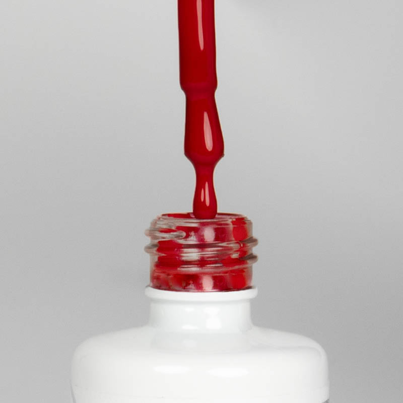 Nahaufnahme einer offenen Longlife UV-Lack Blood Flasche. Die Farbe ist ein dunkles Rot. Der UV-Nagellack tropft am Pinsel herunter.