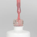 Nahaufnahme einer offenen Longlife UV-Lack Blush Flasche. Die Farbe ist ein helles Rosa. Der UV-Nagellack tropft am Pinsel herunter.