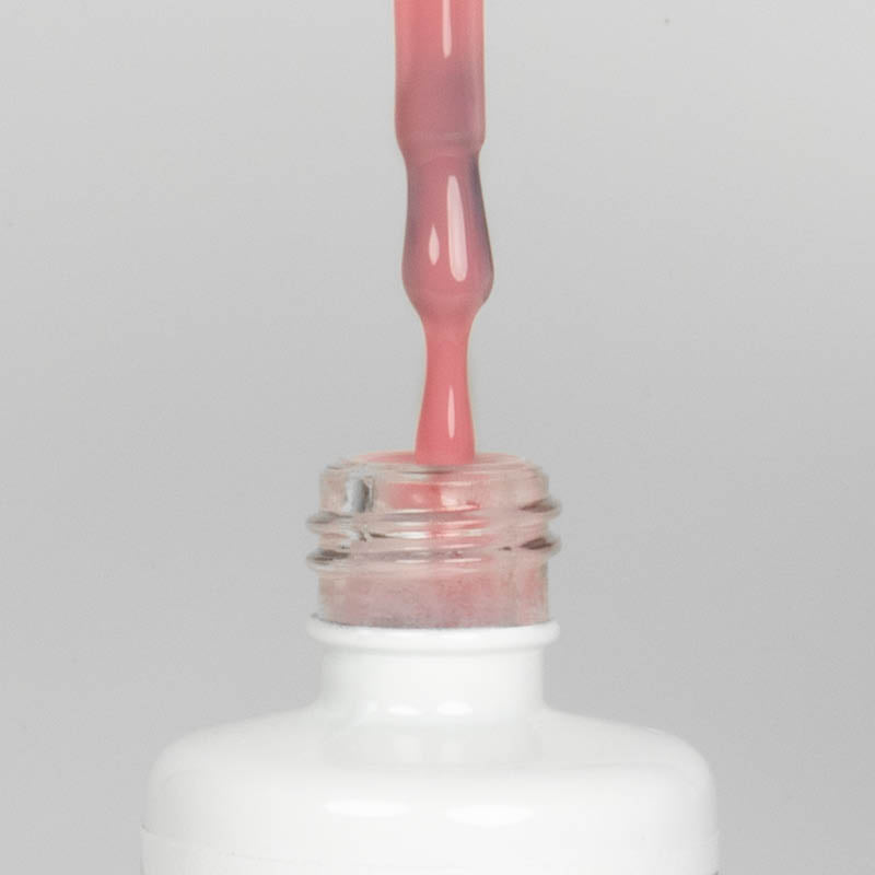 Nahaufnahme einer offenen Longlife UV-Lack Blush Flasche. Die Farbe ist ein helles Rosa. Der UV-Nagellack tropft am Pinsel herunter.