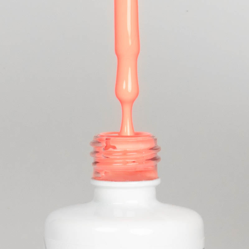 Nahaufnahme einer offenen Longlife UV-Lack Brazil Flasche. Die Farbe ist ein helles Orange mit Rosa-Stich. Der UV-Nagellack tropft am Pinsel herunter.