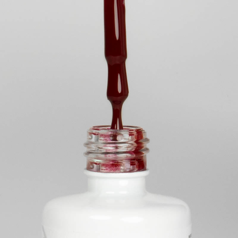 Nahaufnahme einer offenen Longlife UV-Lack Cherry Flasche. Die Farbe ist ein dunkles Rot. Der UV-Nagellack tropft am Pinsel herunter.