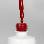 Nahaufnahme einer offenen Longlife UV-Lack Chianti Flasche. Die Farbe ist ein dunkles Rot. Der UV-Nagellack tropft am Pinsel herunter.