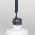 Nahaufnahme einer offenen Longlife UV-Lack Classic Blue Flasche. Die Farbe ist ein dunkles Blau mit geringer Sättigung. Der UV-Nagellack tropft am Pinsel herunter.