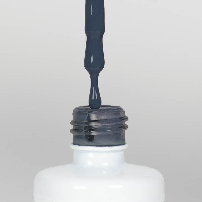 Nahaufnahme einer offenen Longlife UV-Lack Classic Blue Flasche. Die Farbe ist ein dunkles Blau mit geringer Sättigung. Der UV-Nagellack tropft am Pinsel herunter.