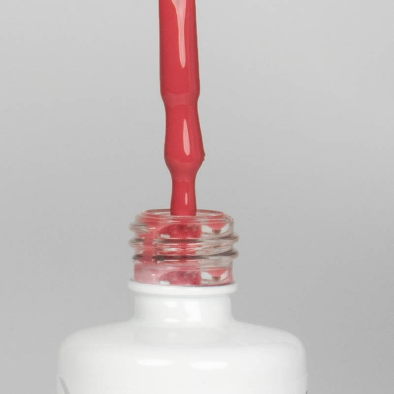 Nahaufnahme einer offenen Longlife UV-Lack Coral Flasche. Die Farbe ist ein dunkles Rosa mit Orange-Stich. Der UV-Nagellack tropft am Pinsel herunter.
