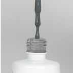 Nahaufnahme einer offenen Longlife UV-Lack Dark Grey Flasche. Die Farbe ist ein dunkles Grau. Der UV-Nagellack tropft am Pinsel herunter.