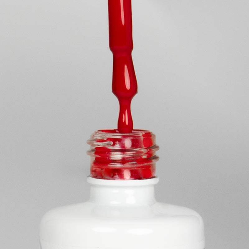 Nahaufnahme einer offenen Longlife UV-Lack Deluxe Red Flasche. Die Farbe ist ein knalliges Rot. Der UV-Nagellack tropft am Pinsel herunter.