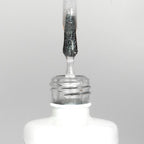 Nahaufnahme einer offenen Longlife UV-Lack Diamond Gloss Flasche. Die Farbe ist transparent mit silber Glitzer-Effekt. Der UV-Nagellack tropft am Pinsel herunter.