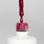 Nahaufnahme einer offenen Longlife UV-Lack Dragon Flasche. Die Farbe ist ein dunkles Pink. Der UV-Nagellack tropft am Pinsel herunter.