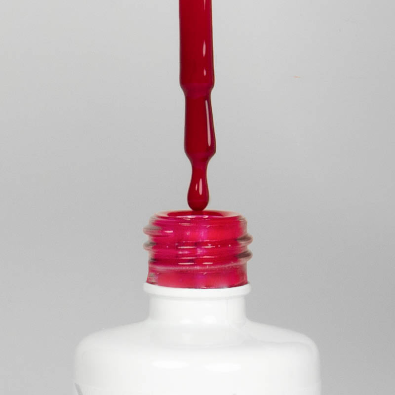 Nahaufnahme einer offenen Longlife UV-Lack Dragonfruit Flasche. Die Farbe ist ein dunkles, knalliges Pink. Der UV-Nagellack tropft am Pinsel herunter.
