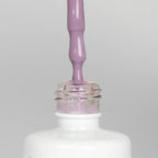 Nahaufnahme einer offenen Longlife UV-Lack Dreamland Flasche. Die Farbe ist ein helles Violett. Der UV-Nagellack tropft am Pinsel herunter.