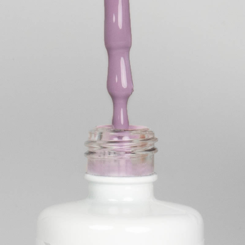 Nahaufnahme einer offenen Longlife UV-Lack Dreamland Flasche. Die Farbe ist ein helles Violett. Der UV-Nagellack tropft am Pinsel herunter.