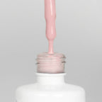 Nahaufnahme einer offenen Longlife UV-Lack Dusky Pink Flasche. Die Farbe ist ein helles Rosa. Der UV-Nagellack tropft am Pinsel herunter.