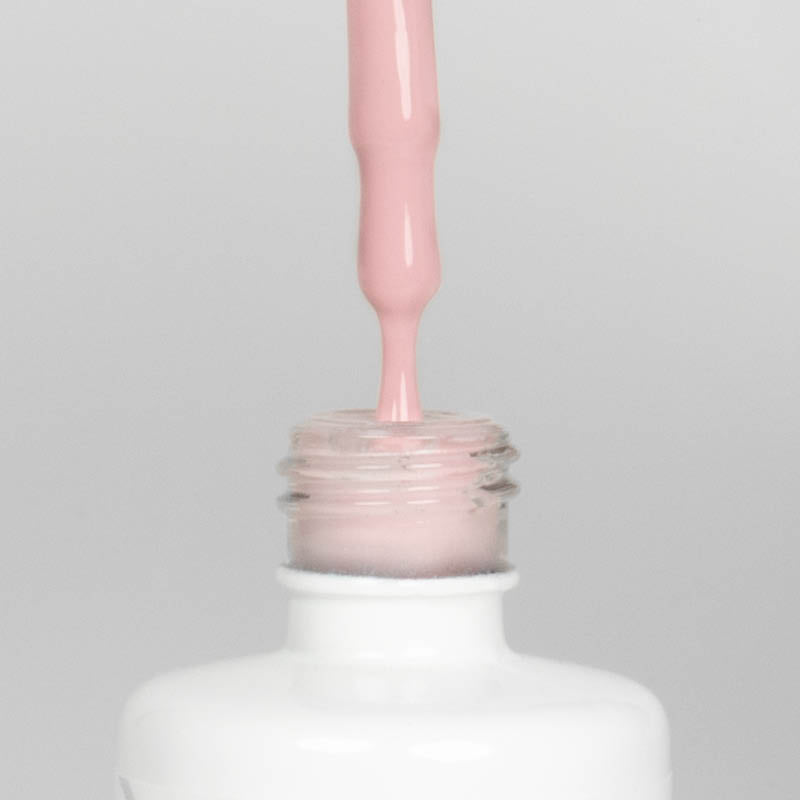 Nahaufnahme einer offenen Longlife UV-Lack Dusky Pink Flasche. Die Farbe ist ein helles Rosa. Der UV-Nagellack tropft am Pinsel herunter.