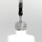 Nahaufnahme einer offenen Longlife UV-Lack Egg Shell Matt Black Flasche. Die Farbe ist transparent mit schwarzen Partikeln. Der UV-Nagellack tropft am Pinsel herunter.