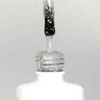 Nahaufnahme einer offenen Longlife UV-Lack Egg Shell Matt Silver Flasche. Die Farbe ist transparent mit silbernen Partikeln. Der UV-Nagellack tropft am Pinsel herunter.