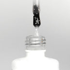 Nahaufnahme einer offenen Longlife UV-Lack Egg Shell Matt White Flasche. Die Farbe ist transparent mit weißen Partikeln. Der UV-Nagellack tropft am Pinsel herunter.