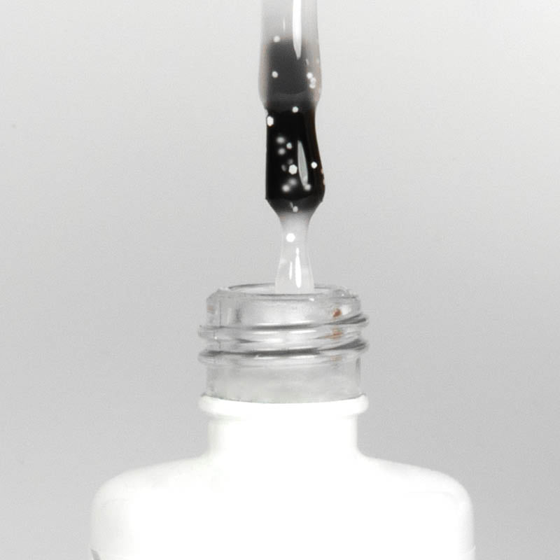 Nahaufnahme einer offenen Longlife UV-Lack Egg Shell Matt White Flasche. Die Farbe ist transparent mit weißen Partikeln. Der UV-Nagellack tropft am Pinsel herunter.