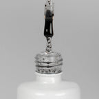 Nahaufnahme einer offenen Longlife UV-Lack Egg Shell Shiny Black Flasche. Die Farbe ist transparent mit schwarzen Partikeln. Der UV-Nagellack tropft am Pinsel herunter.