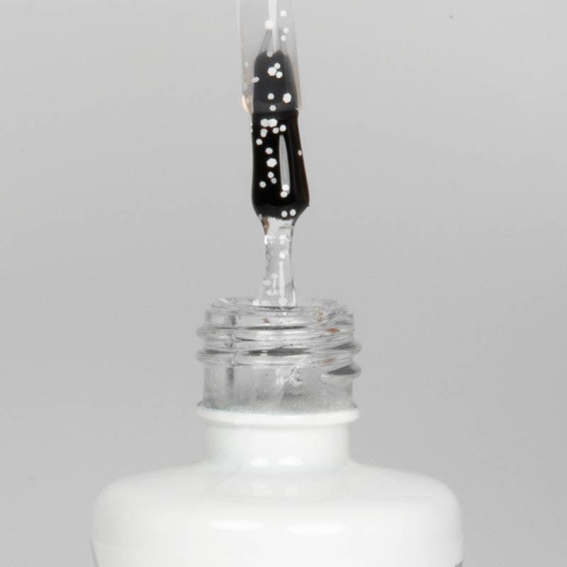 Nahaufnahme einer offenen Longlife UV-Lack Egg Shell Shiny White Flasche. Die Farbe ist transparent mit weißen Pigmenten. Der UV-Nagellack tropft am Pinsel herunter.