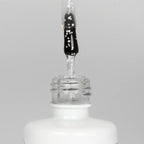 Nahaufnahme einer offenen Longlife UV-Lack Egg Shell Shiny White Flasche. Die Farbe ist transparent mit weißen Pigmenten. Der UV-Nagellack tropft am Pinsel herunter.