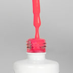 Nahaufnahme einer offenen Longlife UV-Lack Feminista Flasche. Die Farbe ist ein knalliges Pink mit hoher Sättigung. Der UV-Nagellack tropft am Pinsel herunter.