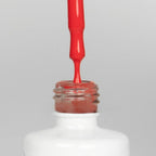 Nahaufnahme einer offenen Longlife UV-Lack Fiery Red Flasche. Die Farbe ist ein helles, knalliges Rot mit hoher Sättigung. Der UV-Nagellack tropft am Pinsel herunter.
