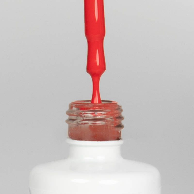 Nahaufnahme einer offenen Longlife UV-Lack Fiery Red Flasche. Die Farbe ist ein helles, knalliges Rot mit hoher Sättigung. Der UV-Nagellack tropft am Pinsel herunter.