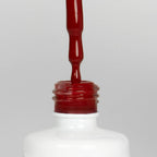 Nahaufnahme einer offenen Longlife UV-Lack Gazpacho Flasche. Die Farbe ist ein dunkles Rot. Der UV-Nagellack tropft am Pinsel herunter.