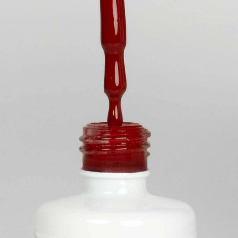 Nahaufnahme einer offenen Longlife UV-Lack Gazpacho Flasche. Die Farbe ist ein dunkles Rot. Der UV-Nagellack tropft am Pinsel herunter.