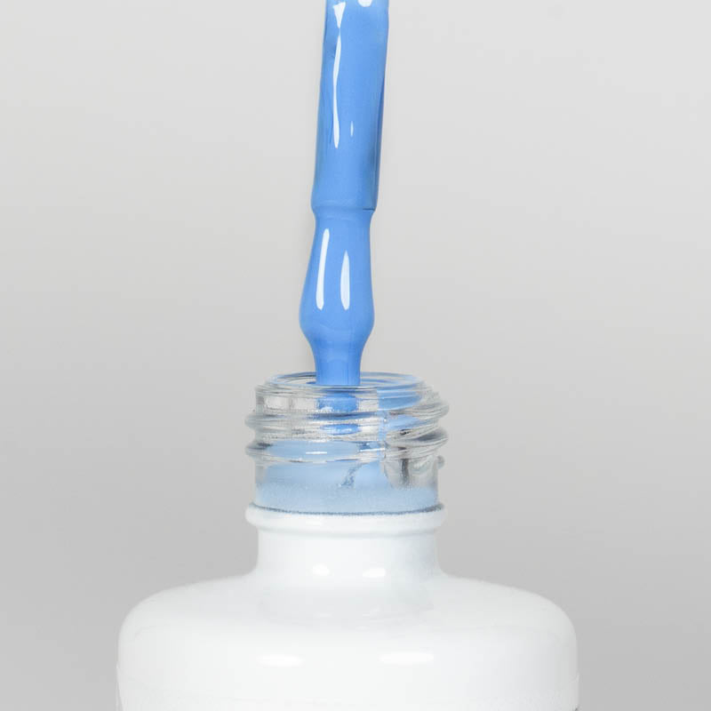 Nahaufnahme einer offenen Longlife UV-Lack Intensive Blue Flasche. Die Farbe ist ein helles Blau mit hoher Sättigung. Der UV-Nagellack tropft am Pinsel herunter.