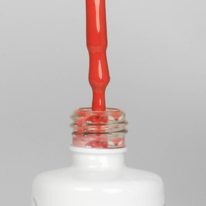 Nahaufnahme einer offenen Longlife UV-Lack Koi Flasche. Die Farbe ist ein helles Orange-Rot mit hoher Sättigung. Der UV-Nagellack tropft am Pinsel herunter.