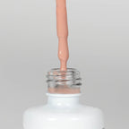 Nahaufnahme einer offenen Longlife UV-Lack Light Nude Flasche. Die Farbe ist ein helles Nude. Der UV-Nagellack tropft am Pinsel herunter.