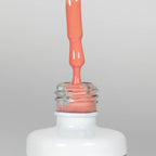 Nahaufnahme einer offenen Longlife UV-Lack Living Coral Flasche. Die Farbe ist ein helles Orange mit hoher Sättigung. Der UV-Nagellack tropft am Pinsel herunter.