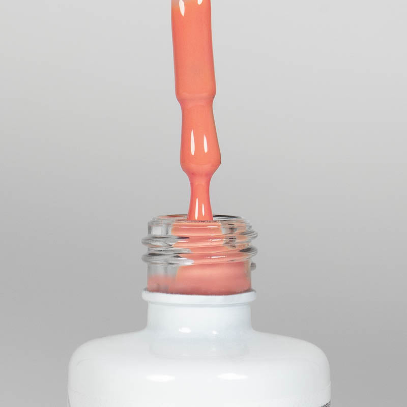 Nahaufnahme einer offenen Longlife UV-Lack Living Coral Flasche. Die Farbe ist ein helles Orange mit hoher Sättigung. Der UV-Nagellack tropft am Pinsel herunter.