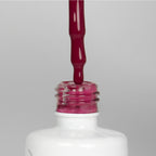 Nahaufnahme einer offenen Longlife UV-Lack Lolli Pink Flasche. Die Farbe ist ein dunkles Rosa. Der UV-Nagellack tropft am Pinsel herunter.