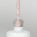 Nahaufnahme einer offenen Longlife UV-Lack Mademoiselle Flasche. Die Farbe ist ein helles Nude. Der UV-Nagellack tropft am Pinsel herunter.